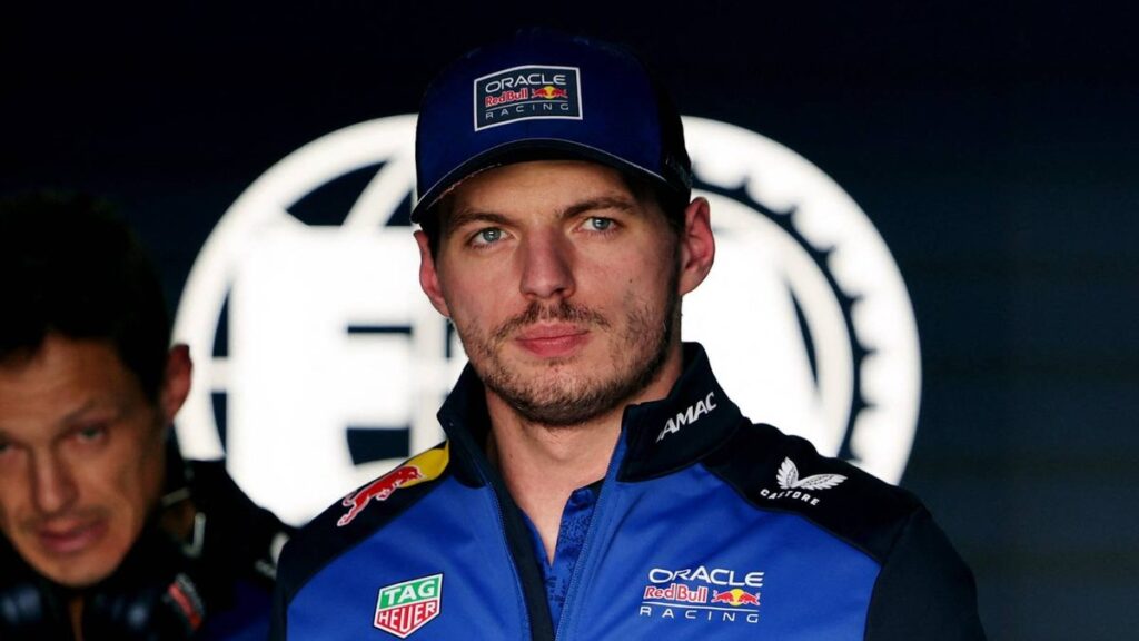 Max Verstappen looking visibly frustrated in his Red Bull racing suit in the team garage