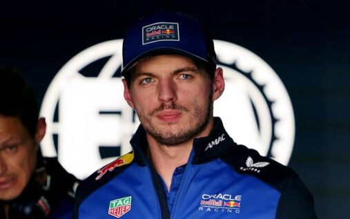 Max Verstappen looking visibly frustrated in his Red Bull racing suit in the team garage