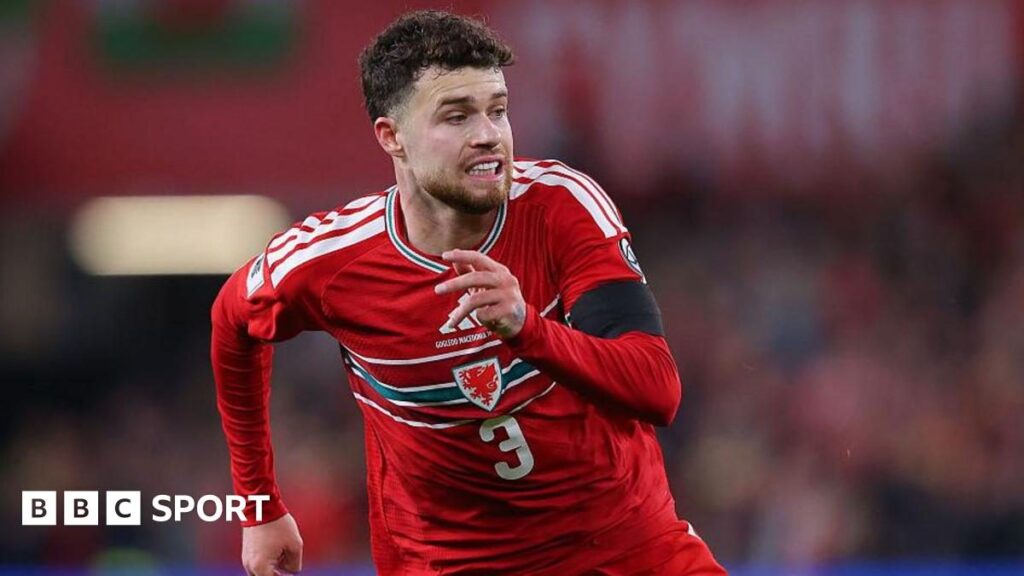 Neco Williams in action for Wales wearing the red international kit