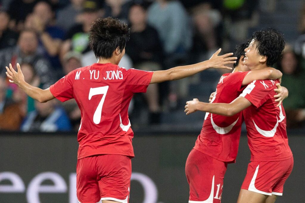 North Korean women's football team celebrating on the pitch in their national kits