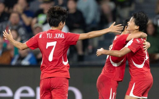 North Korean women's football team celebrating on the pitch in their national kits