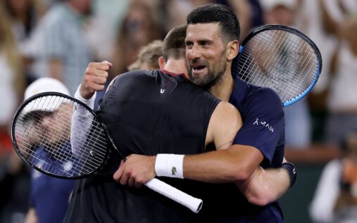 Novak Djokovic holding his right shoulder and looking visibly exhausted on a tennis court