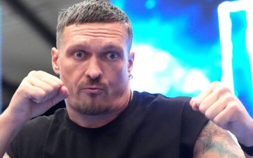 Oleksandr Usyk celebrating with his heavyweight championship belts in the ring