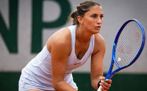 Panna Udvardy preparing to serve during a professional tennis match on a clay court.