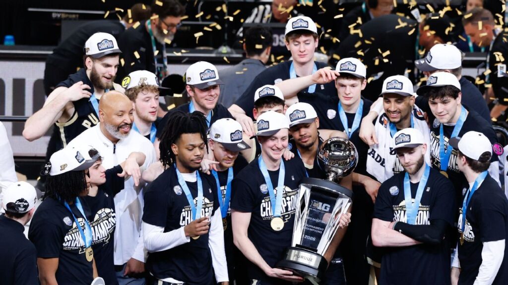 Purdue basketball players celebrating with the Big Ten tournament championship trophy after defeating Michigan