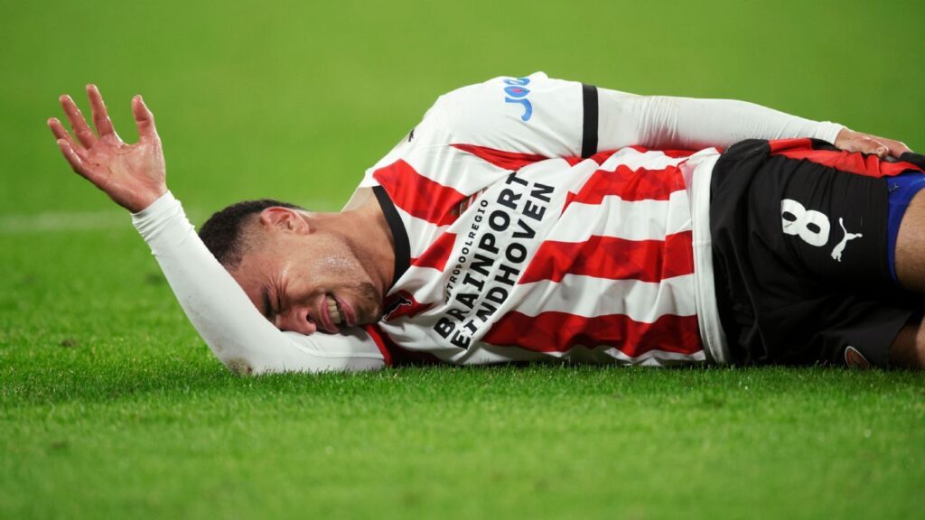 USMNT defender Sergiño Dest clutching his left leg after suffering a hamstring injury for PSV Eindhoven