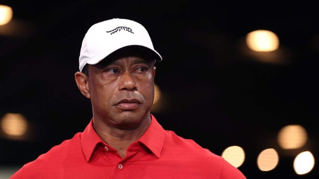 Tiger Woods wearing a golf cap and looking contemplative on a golf course