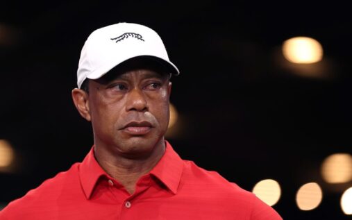 Tiger Woods wearing a golf cap and looking contemplative on a golf course