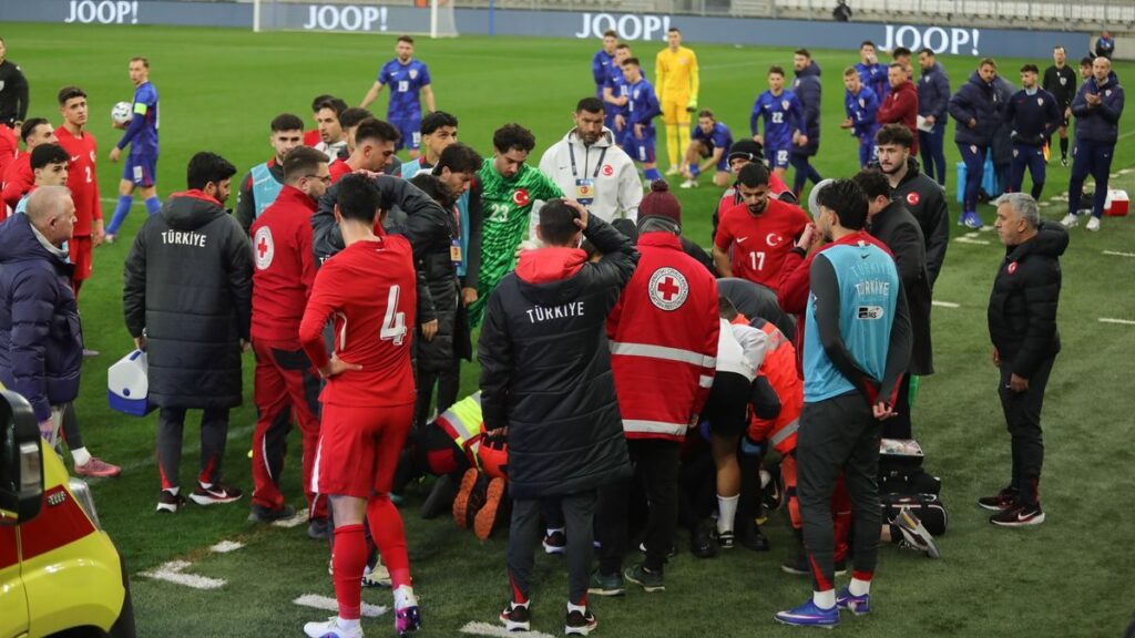 Medical staff treating a person on a stretcher inside a football stadium