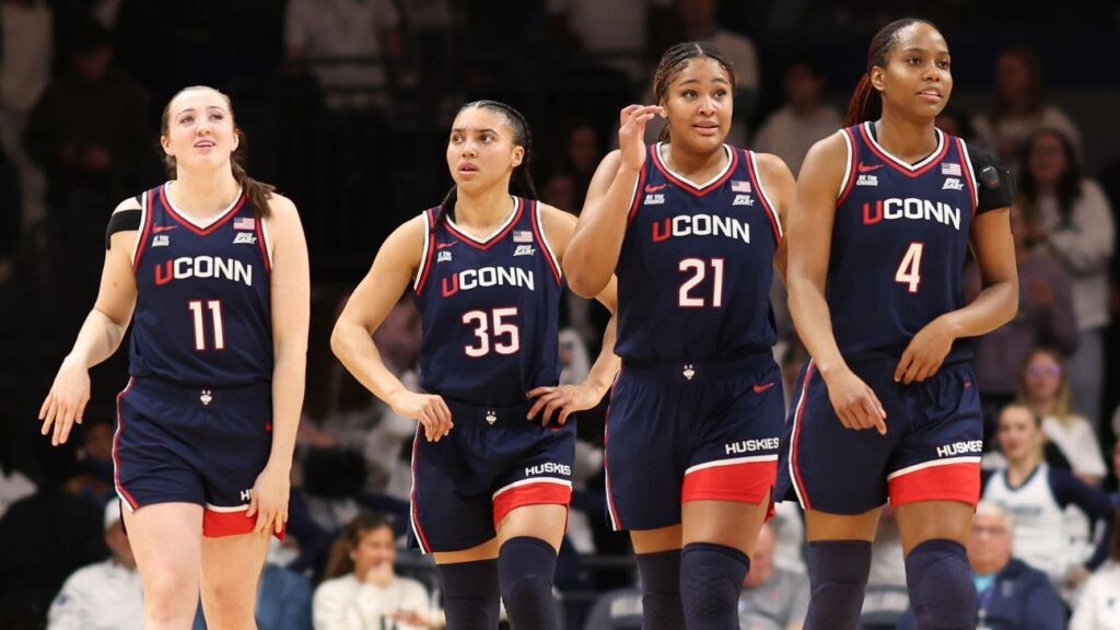 UConn Huskies players celebrating on the court during the NCAA women's basketball tournament