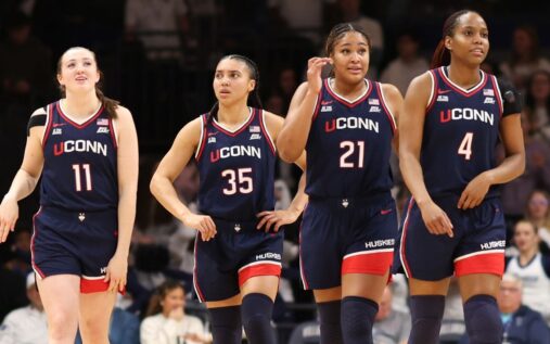 UConn Huskies players celebrating on the court during the NCAA women's basketball tournament