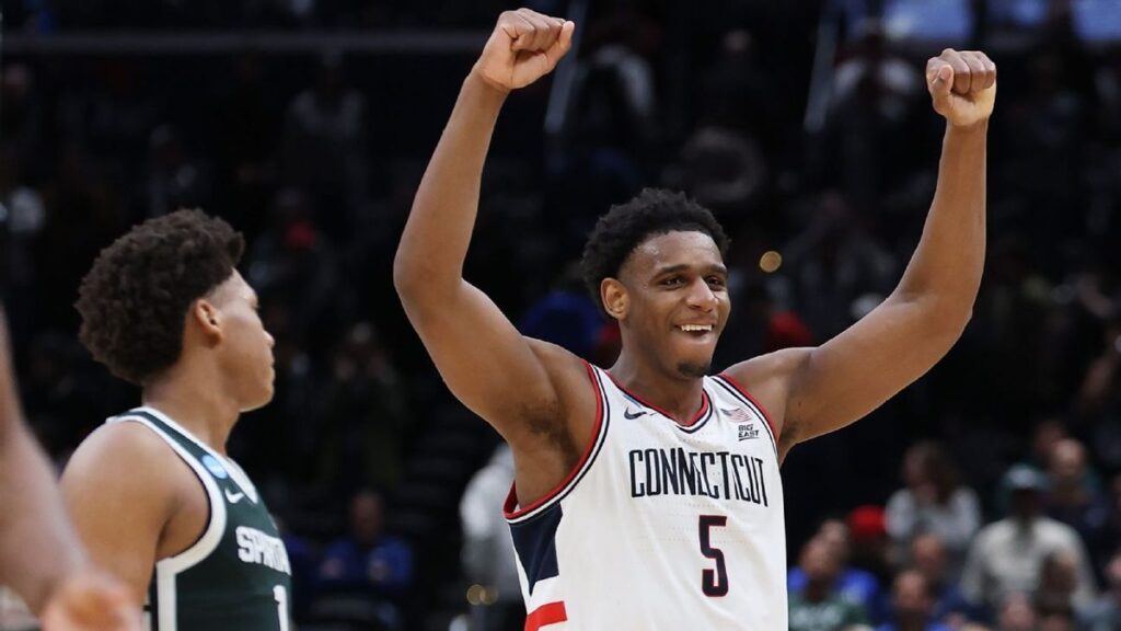 UConn players celebrating on the court after defeating Michigan State in the NCAA Tournament Sweet 16