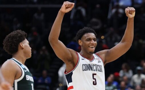 UConn players celebrating on the court after defeating Michigan State in the NCAA Tournament Sweet 16