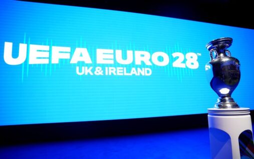 Fans holding national flags in a packed stadium during an international football match