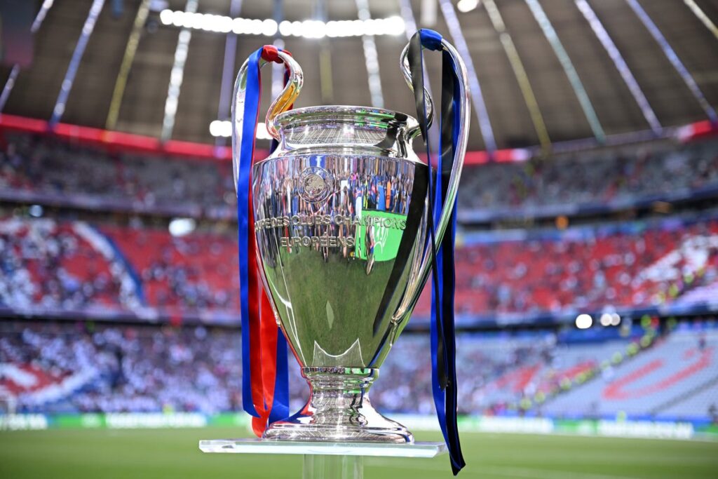 The Champions League trophy displayed on a podium inside a football stadium