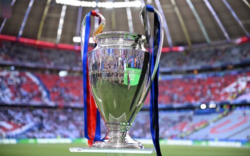 The Champions League trophy displayed on a podium inside a football stadium