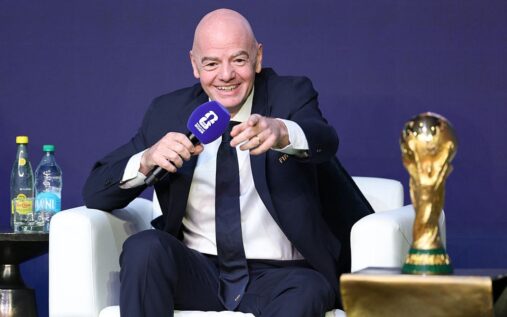 Soccer fans in a large stadium holding flags of the USA, Mexico, and Canada