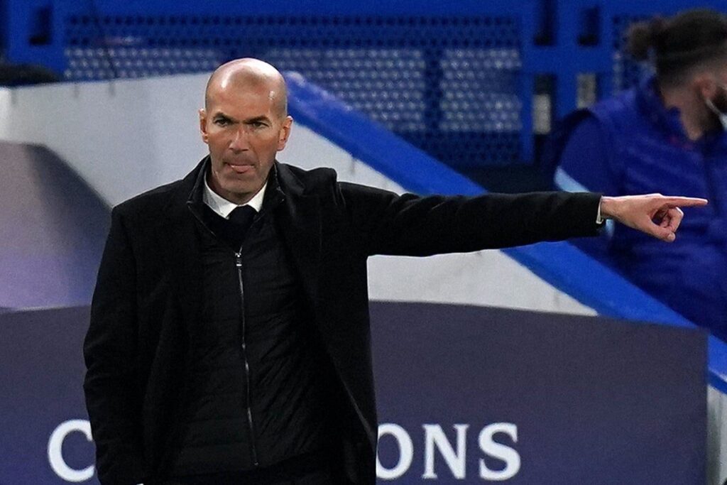 Zinedine Zidane standing on the touchline in a suit managing a football match