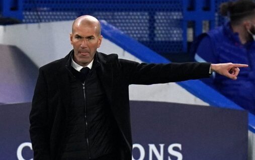 Zinedine Zidane standing on the touchline in a suit managing a football match
