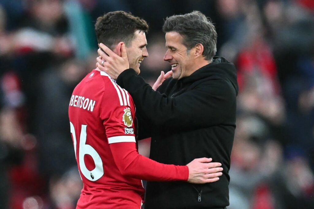 Andy Robertson waving to Liverpool fans on the pitch at Anfield wearing his red match kit