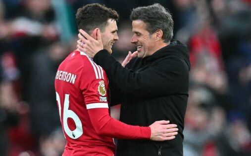 Andy Robertson waving to Liverpool fans on the pitch at Anfield wearing his red match kit