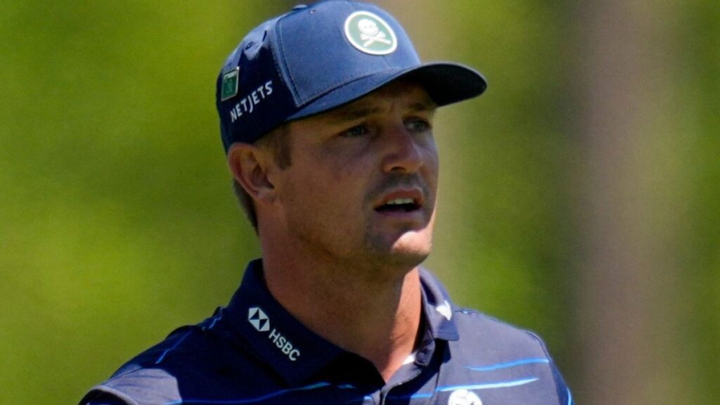 Bryson DeChambeau grimacing while holding his wrist during a golf tournament