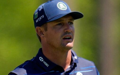 Bryson DeChambeau grimacing while holding his wrist during a golf tournament