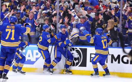 Buffalo Sabres players celebrating a goal against the Boston Bruins on the ice
