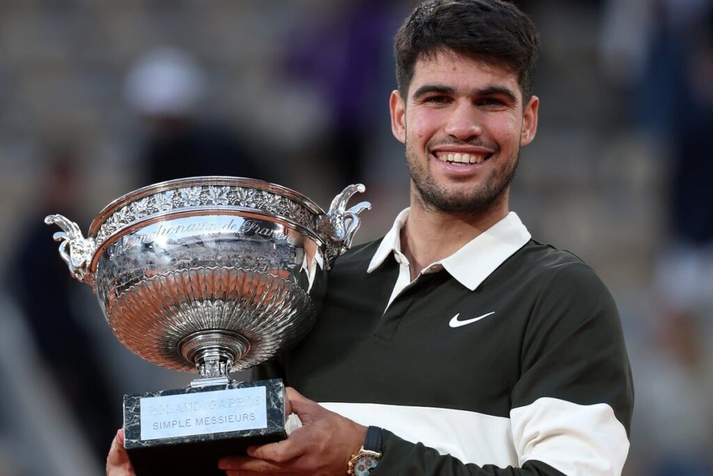 Carlos Alcaraz holding his wrist in discomfort during a clay-court tennis match