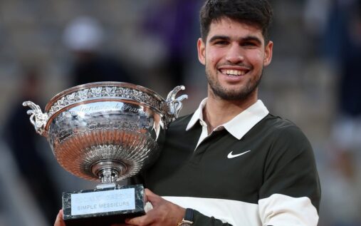 Carlos Alcaraz holding his wrist in discomfort during a clay-court tennis match