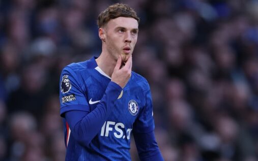 Cole Palmer looking thoughtful on the pitch in a Chelsea football kit