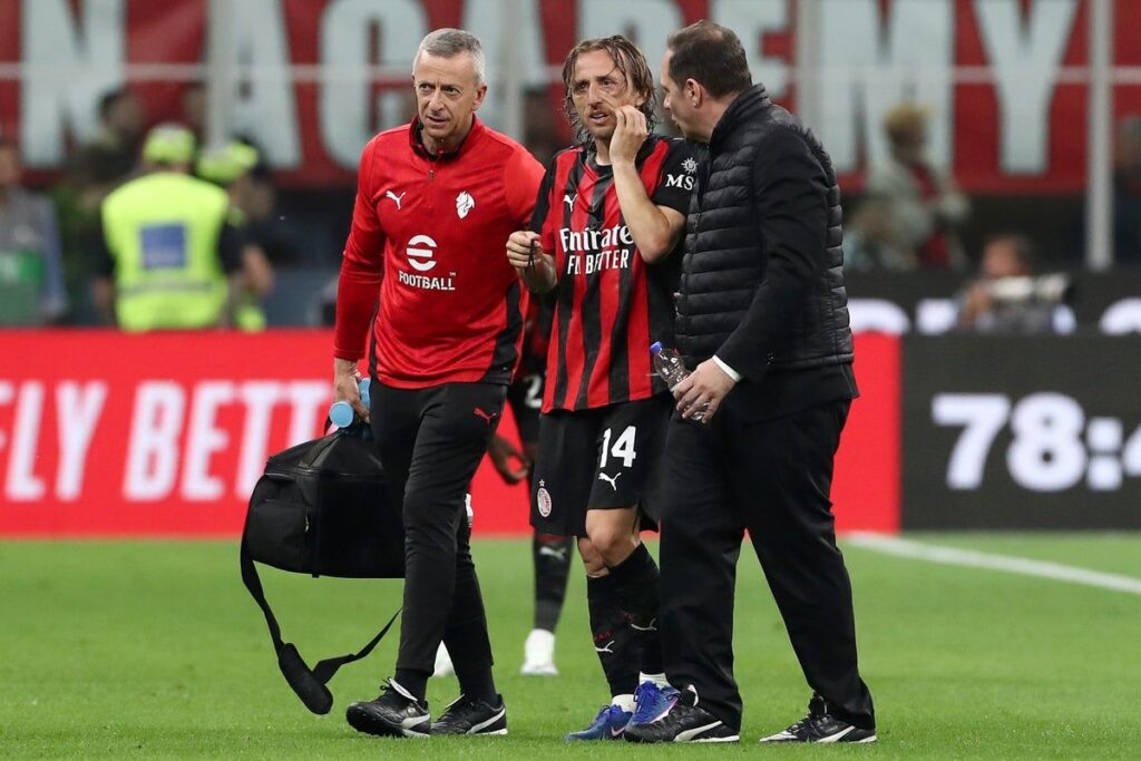 Luka Modric wearing an AC Milan kit looking injured on the football pitch