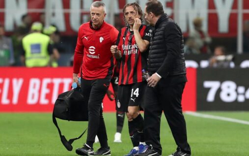 Luka Modric wearing an AC Milan kit looking injured on the football pitch