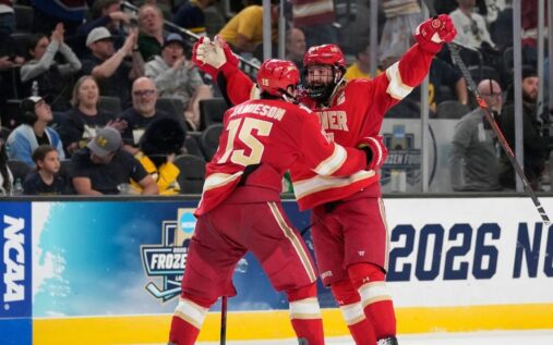 Denver Pioneers players celebrating their double-overtime victory on the ice against the Michigan Wolverines