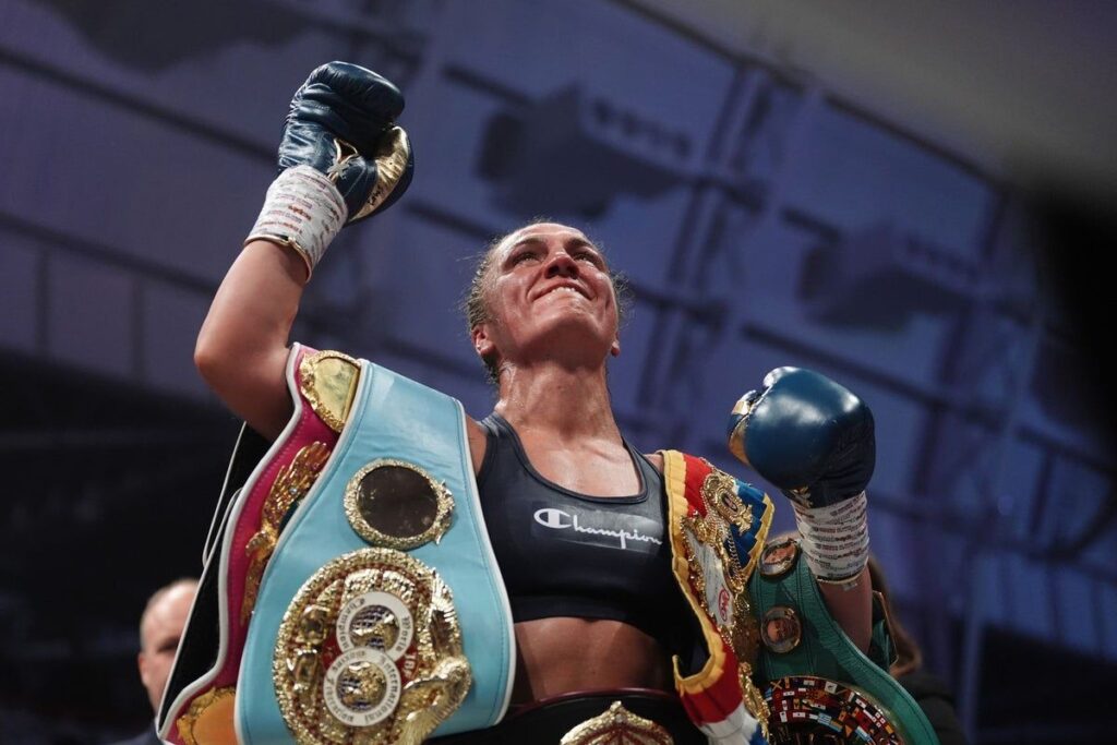 Ellie Scotney celebrating in the ring with her undisputed super-bantamweight championship belts