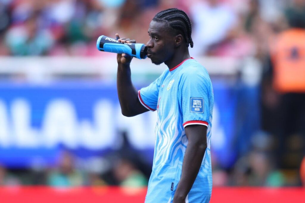 Football players taking a hydration break during a hot match at a stadium