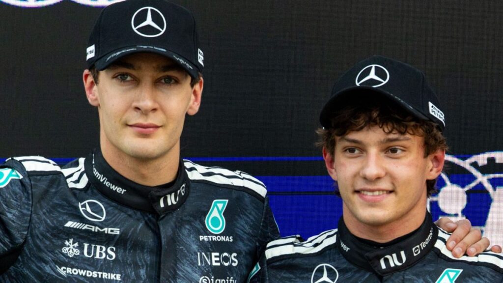 George Russell and Kimi Antonelli walking together in Mercedes team gear at a Formula 1 race track