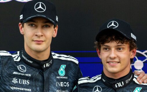 George Russell and Kimi Antonelli walking together in Mercedes team gear at a Formula 1 race track