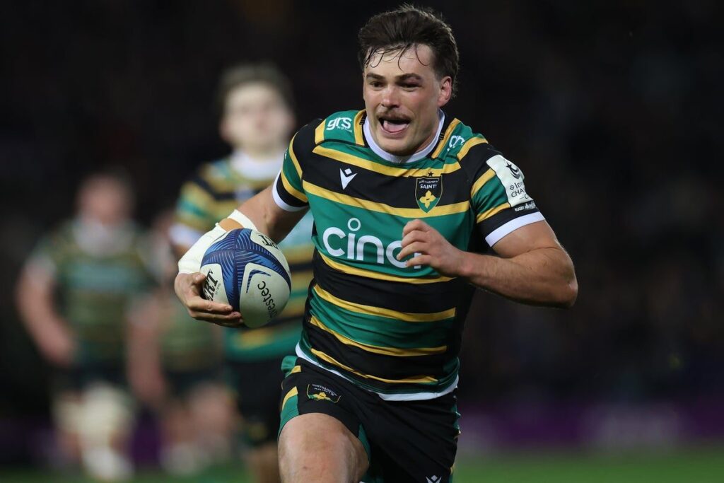 George Furbank running with the ball in a Northampton Saints rugby kit