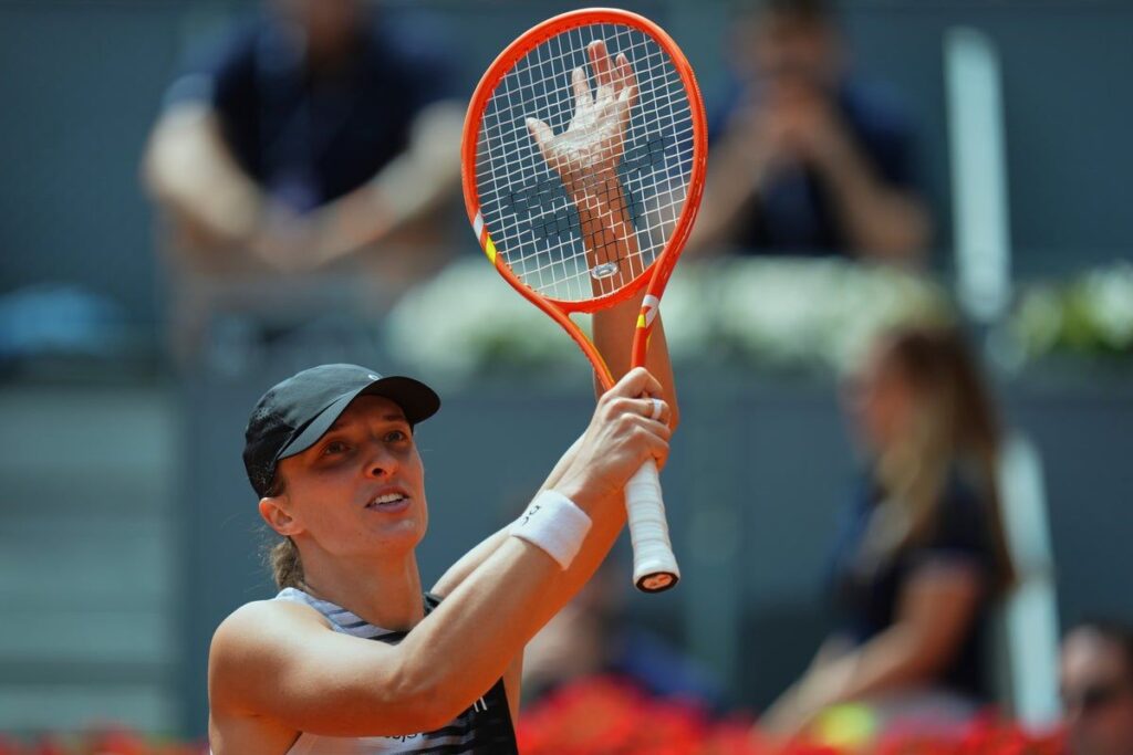 Iga Swiatek hitting a forehand on a clay court during her first-round victory at the Madrid Open