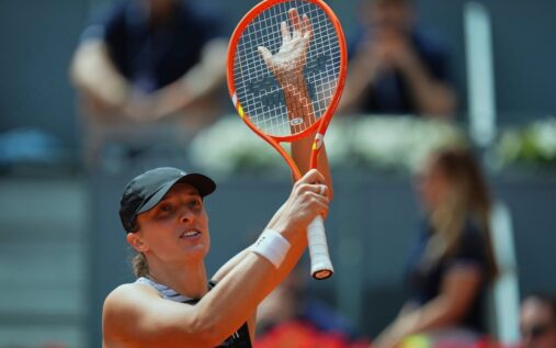 Iga Swiatek hitting a forehand on a clay court during her first-round victory at the Madrid Open