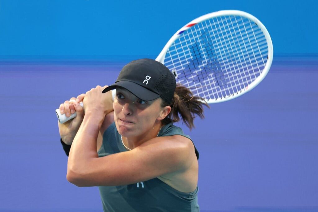 Iga Swiatek preparing to hit a forehand return on a clay tennis court