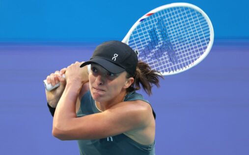 Iga Swiatek preparing to hit a forehand return on a clay tennis court