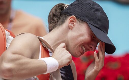 Iga Swiatek appearing visibly distressed and receiving medical attention on a clay tennis court