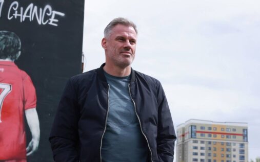 Jamie Carragher speaking into a microphone during a broadcast at Anfield