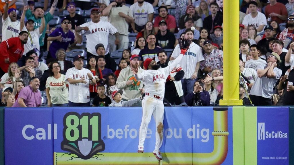 Los Angeles Angels outfielder Jo Adell leaping over the outfield wall to make a spectacular home run-robbing catch