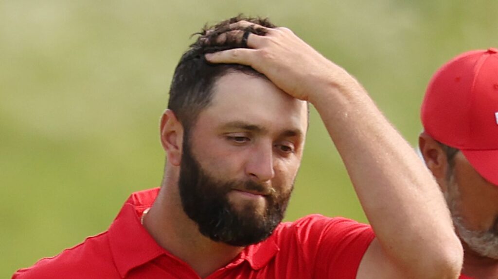Jon Rahm smiling and holding a golf club during a LIV Golf tournament