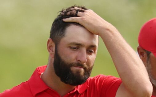 Jon Rahm smiling and holding a golf club during a LIV Golf tournament