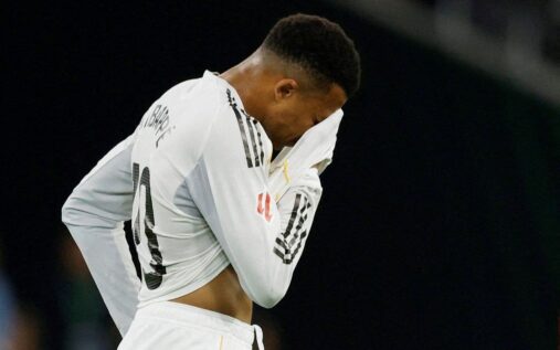 Kylian Mbappe looks dejected while sitting injured on the football pitch