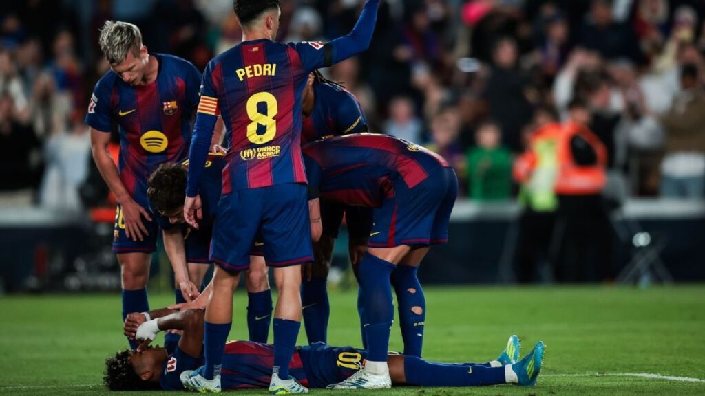 Lamine Yamal clutching his hamstring on the pitch while receiving medical attention at Camp Nou